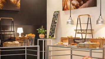 Une vitrine de boulangerie présentant diverses pâtisseries, un menu écrit à la craie et une plante.