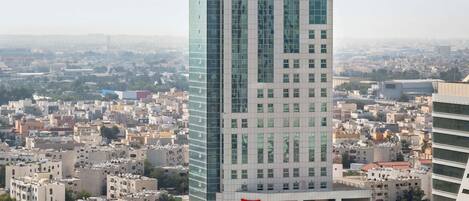 A high-rise hotel with a modern glass facade, multiple floors, and a prominent red logo.