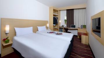 Een hotelkamer met een groot bed, een bureau met een laptop, een spiegel en een televisie.