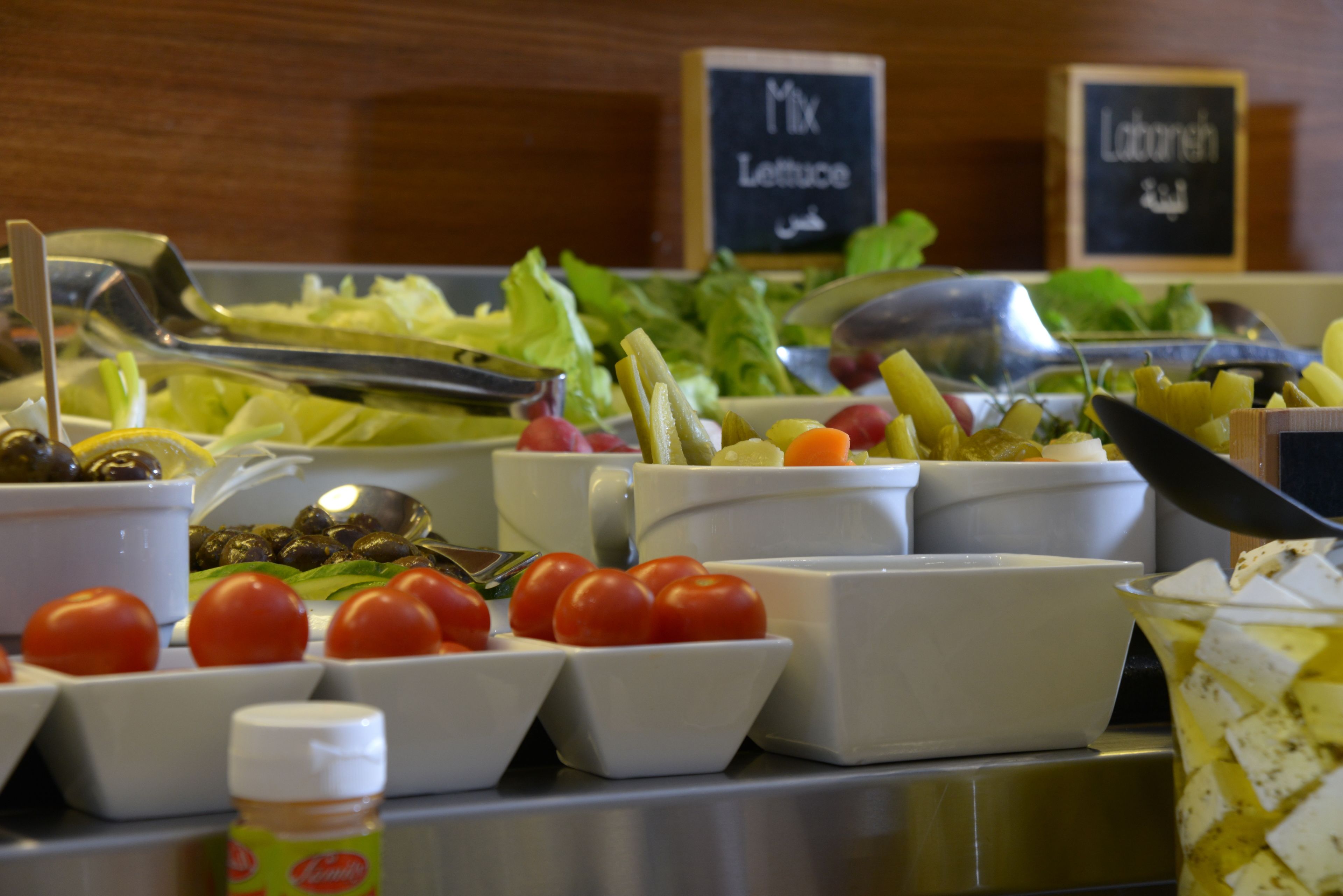 Un buffet de salades proposant une variété de légumes et de condiments.