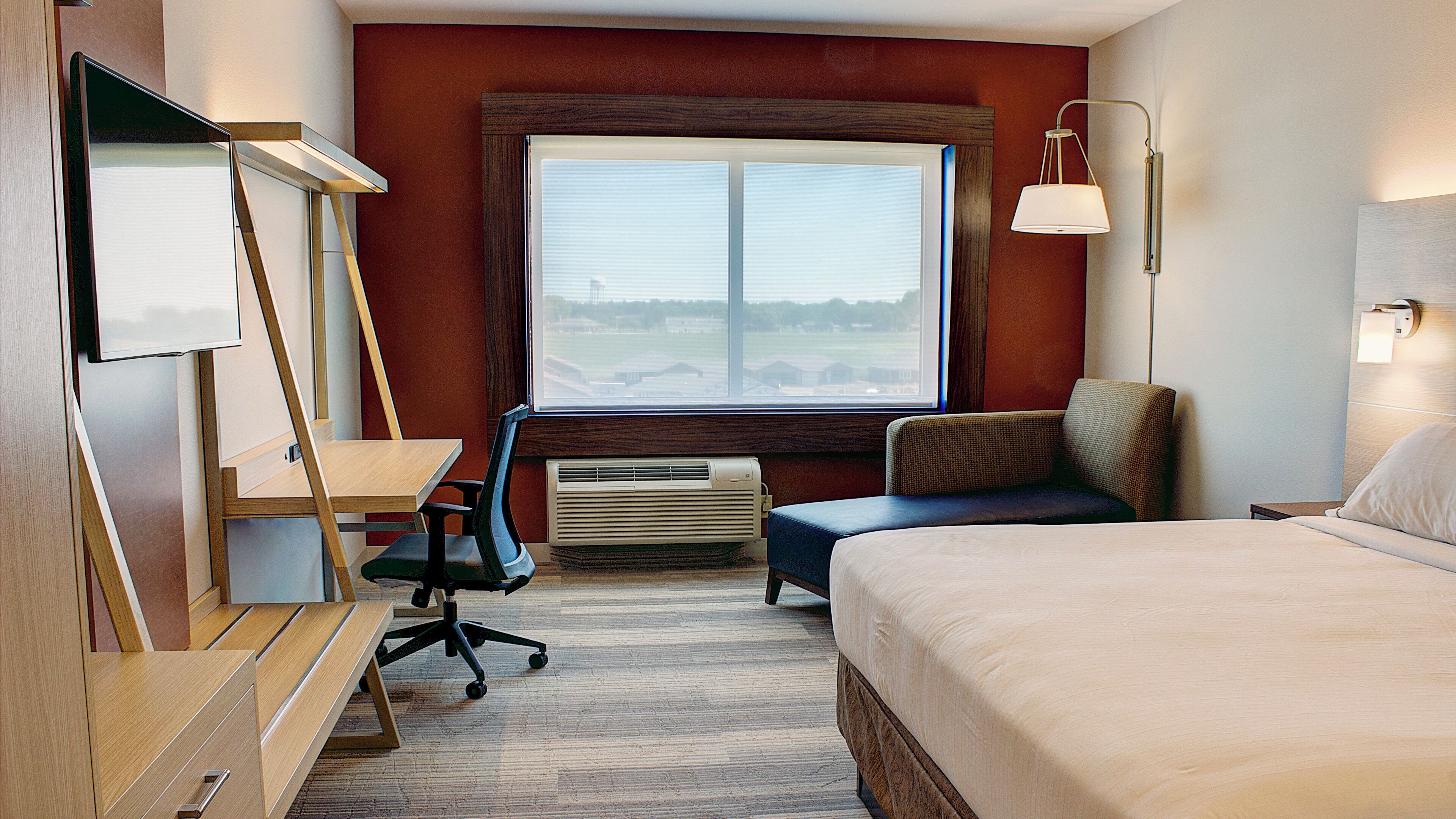 Ein Hotelzimmer mit Bett, Schreibtisch, Stuhl und einem Fenster mit Blick.