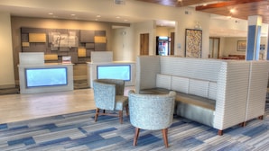 A hotel lobby with a reception desk, seating area, and a refrigerator.