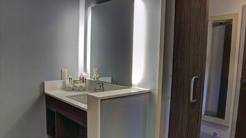 Un baño con lavamanos doble, un espejo grande y una puerta de madera.