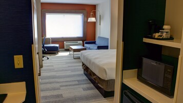 Una habitación de hotel con cama, escritorio, silla, sofá, televisión y ventana.