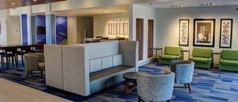 A hotel lobby with a seating area, a reception desk, and a bar.