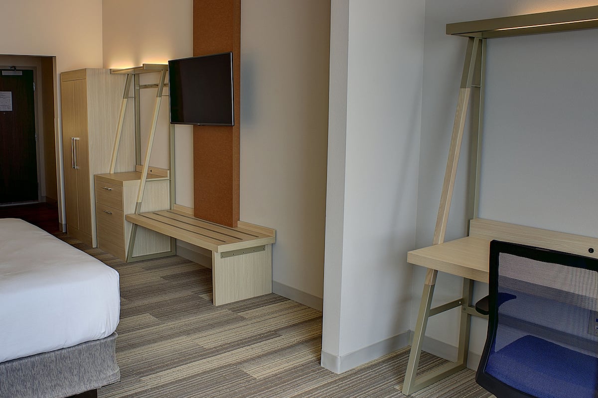 A hotel room with two beds, a desk, a chair, a TV, and a wardrobe.