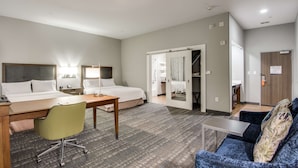 A hotel room with a bed, desk, chair, and a sofa.