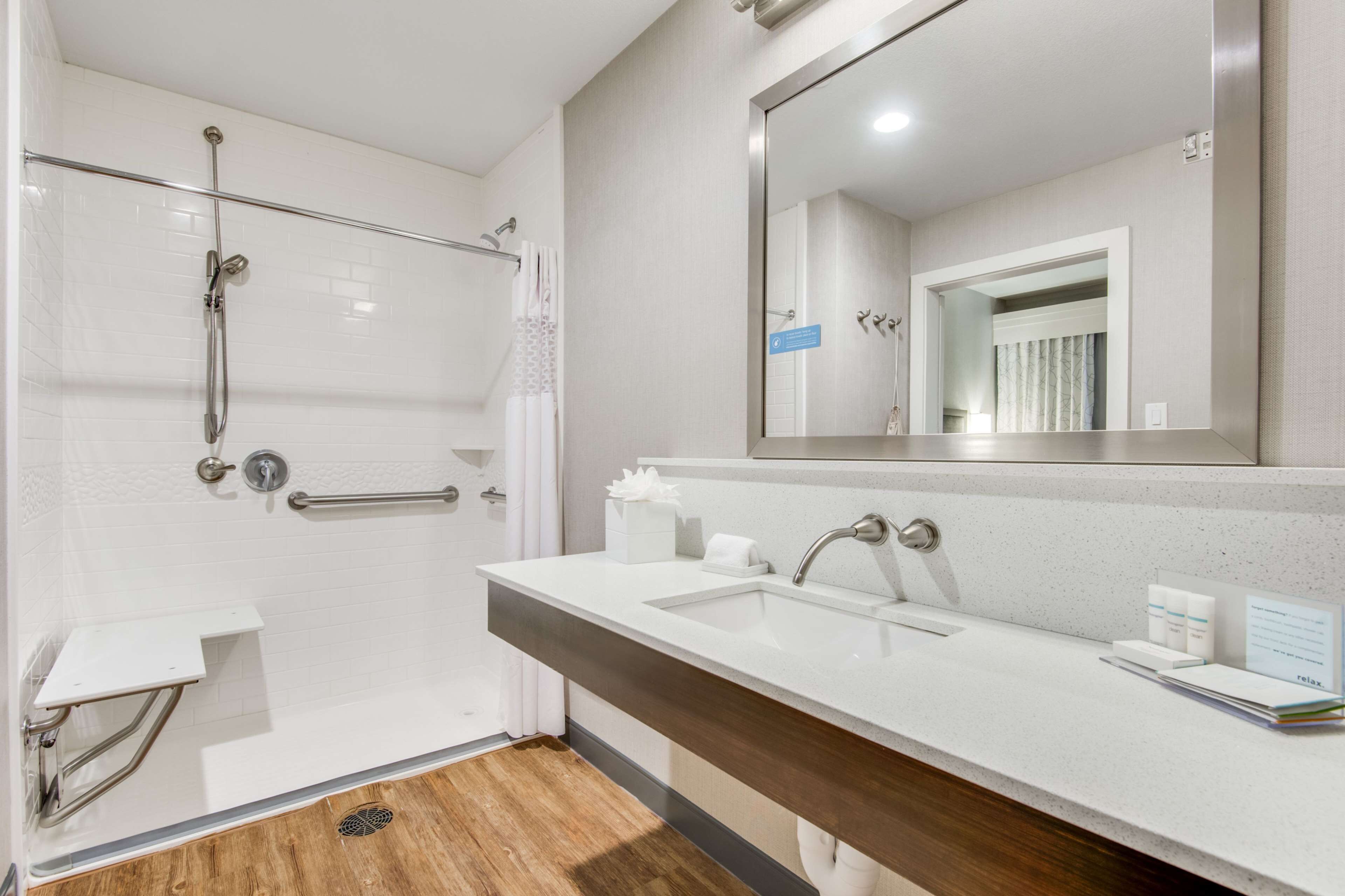 Un baño moderno con ducha, lavamanos y un espejo grande.