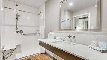 Un baño moderno con ducha, lavamanos y un espejo grande.