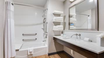 A modern bathroom with a bathtub, shower, and vanity with a mirror.