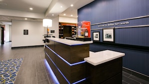 A reception area with a modern design, featuring a reception desk, a wall-mounted sign, and a blue accent wall.