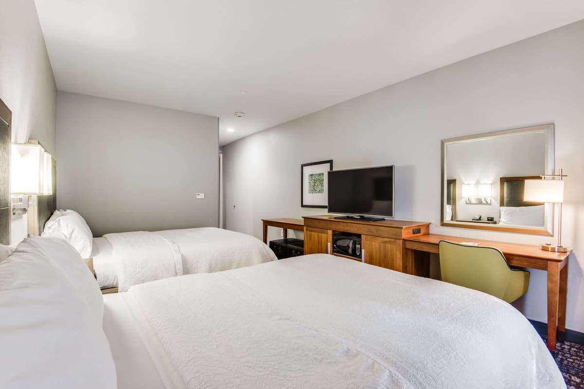 Une chambre d’hôtel avec deux lits, un bureau avec une télévision et un miroir.