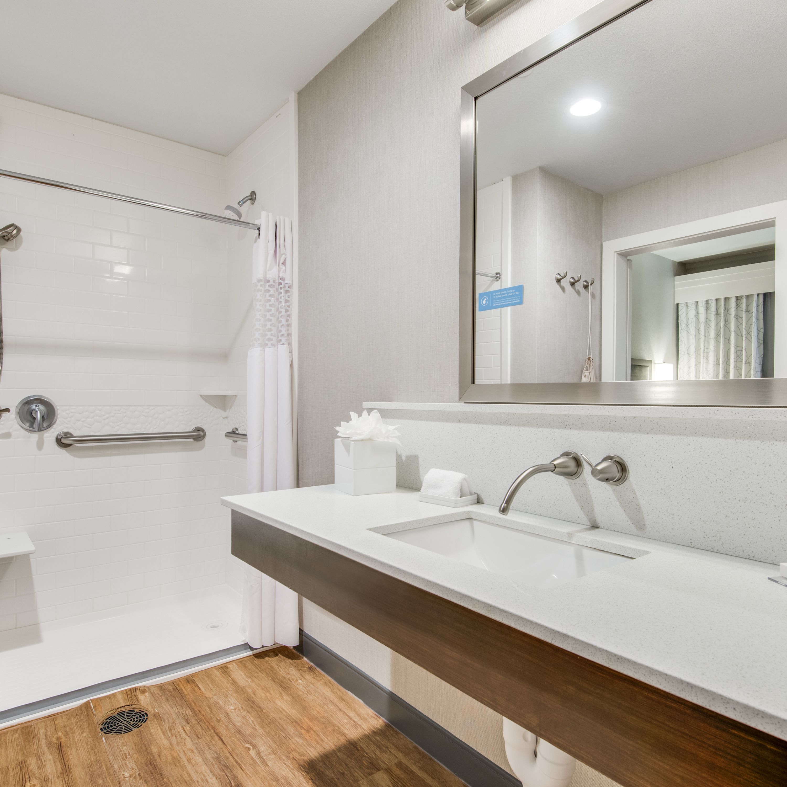 Un baño moderno con ducha, lavamanos y espejo.