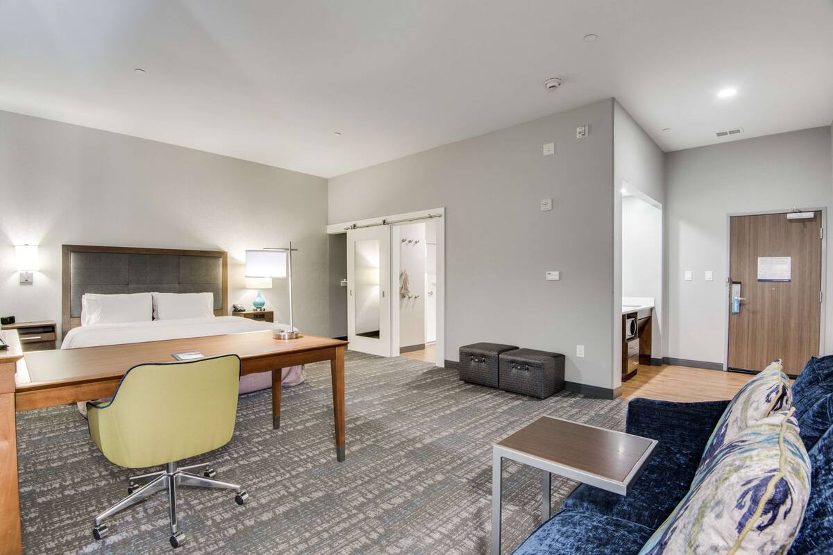 Une chambre d’hôtel comprenant un lit, un bureau, une chaise, un canapé et une petite table.