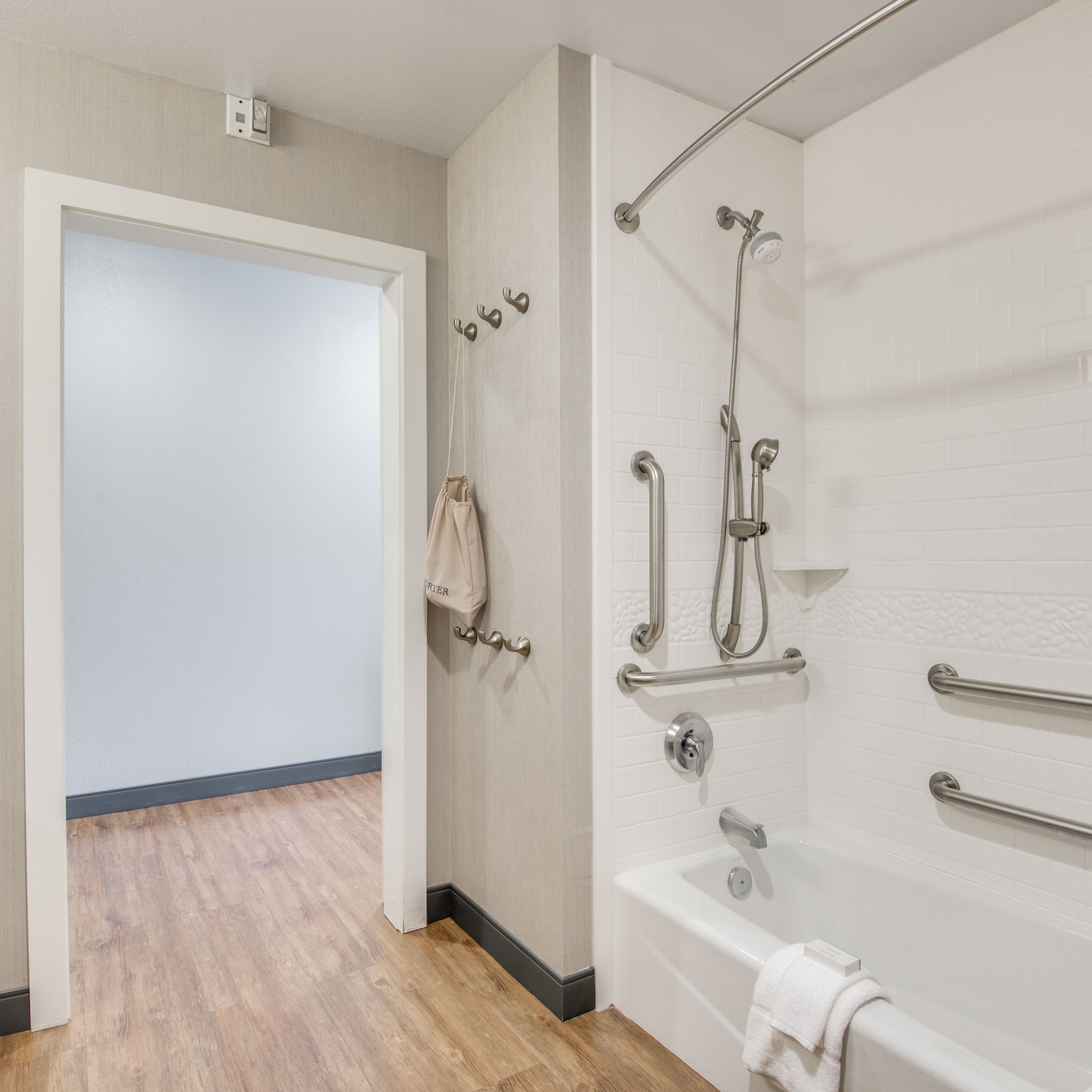 A modern bathroom with a bathtub, shower, and grab bars.