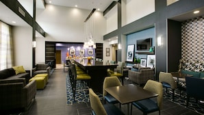 A modern hotel lobby with a bar area, seating arrangements, and a reception desk.