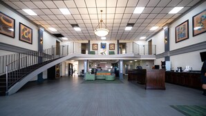 A spacious lobby with a staircase, seating area, and a reception desk.