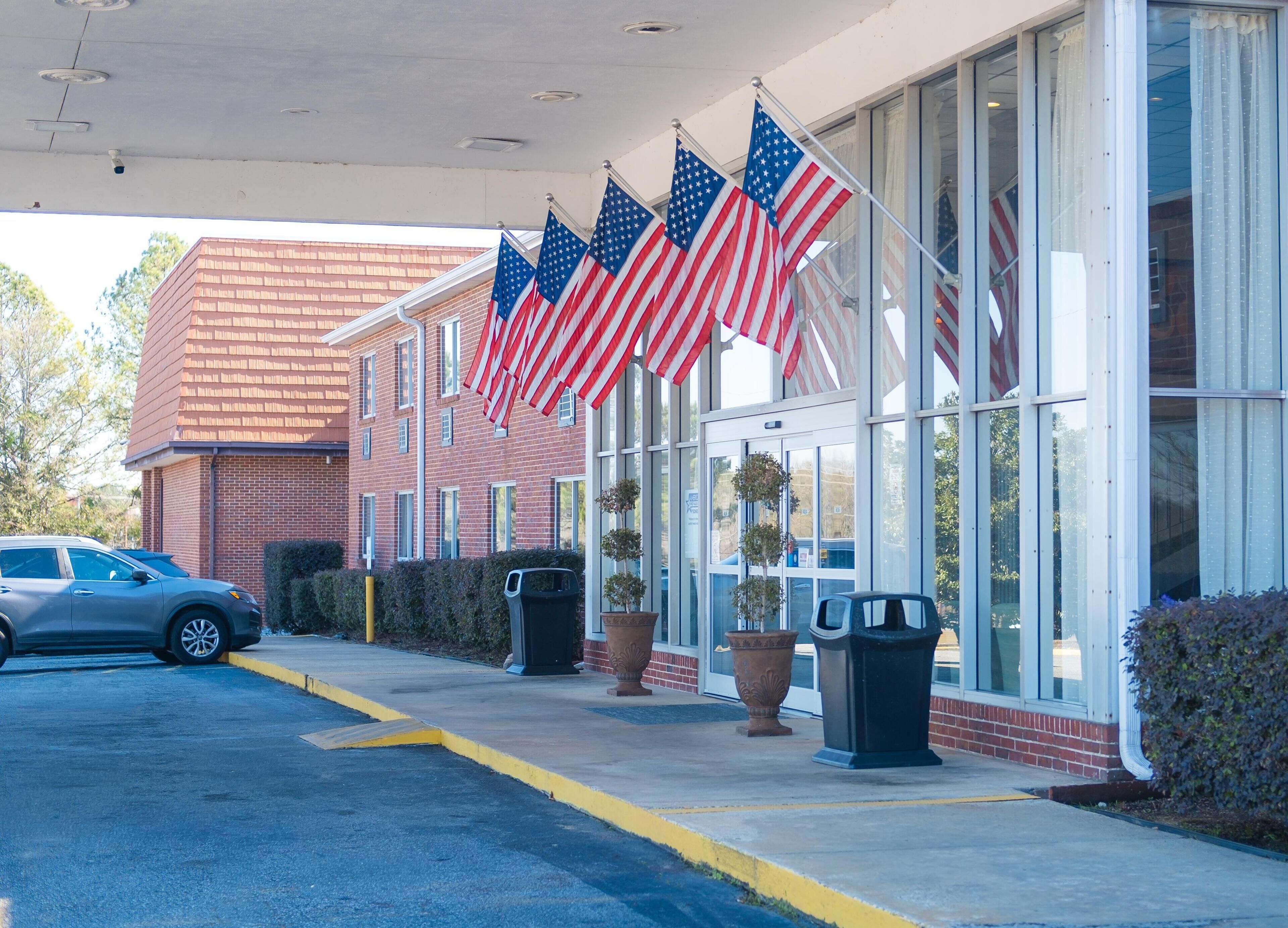 A building with American flags, a parking lot, and a brick facade.
