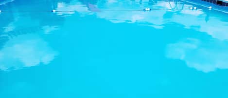 En säsongsöppen utomhuspool, parasoller och solstolar