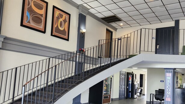 A spacious lobby with a central staircase, a reception desk, and artwork on the walls.