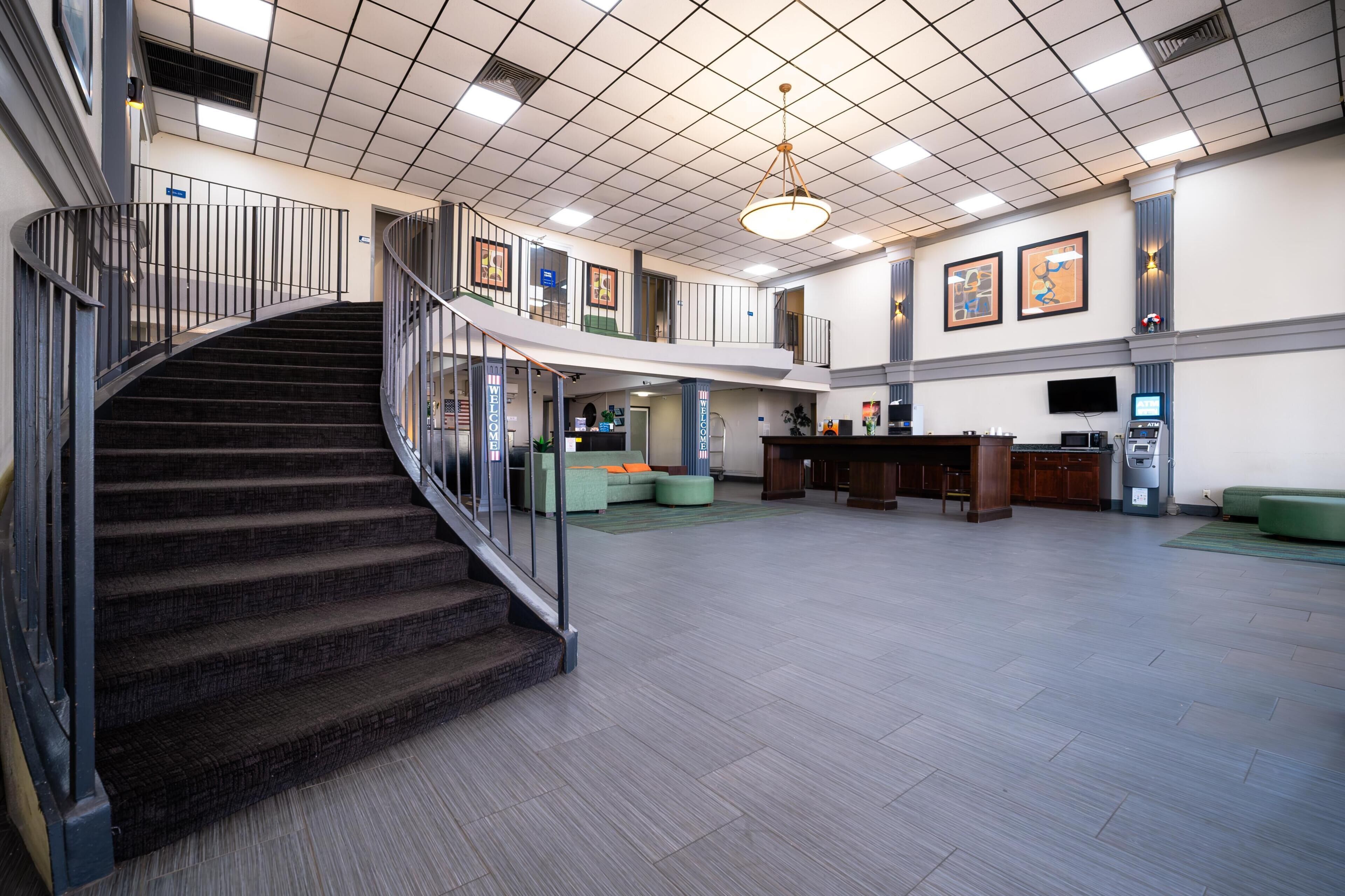 A spacious lobby with a curved staircase, a reception desk, and a seating area.