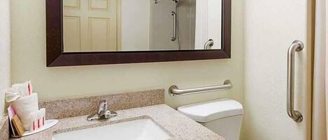 Une salle de bain avec un lavabo, un miroir et des toilettes.