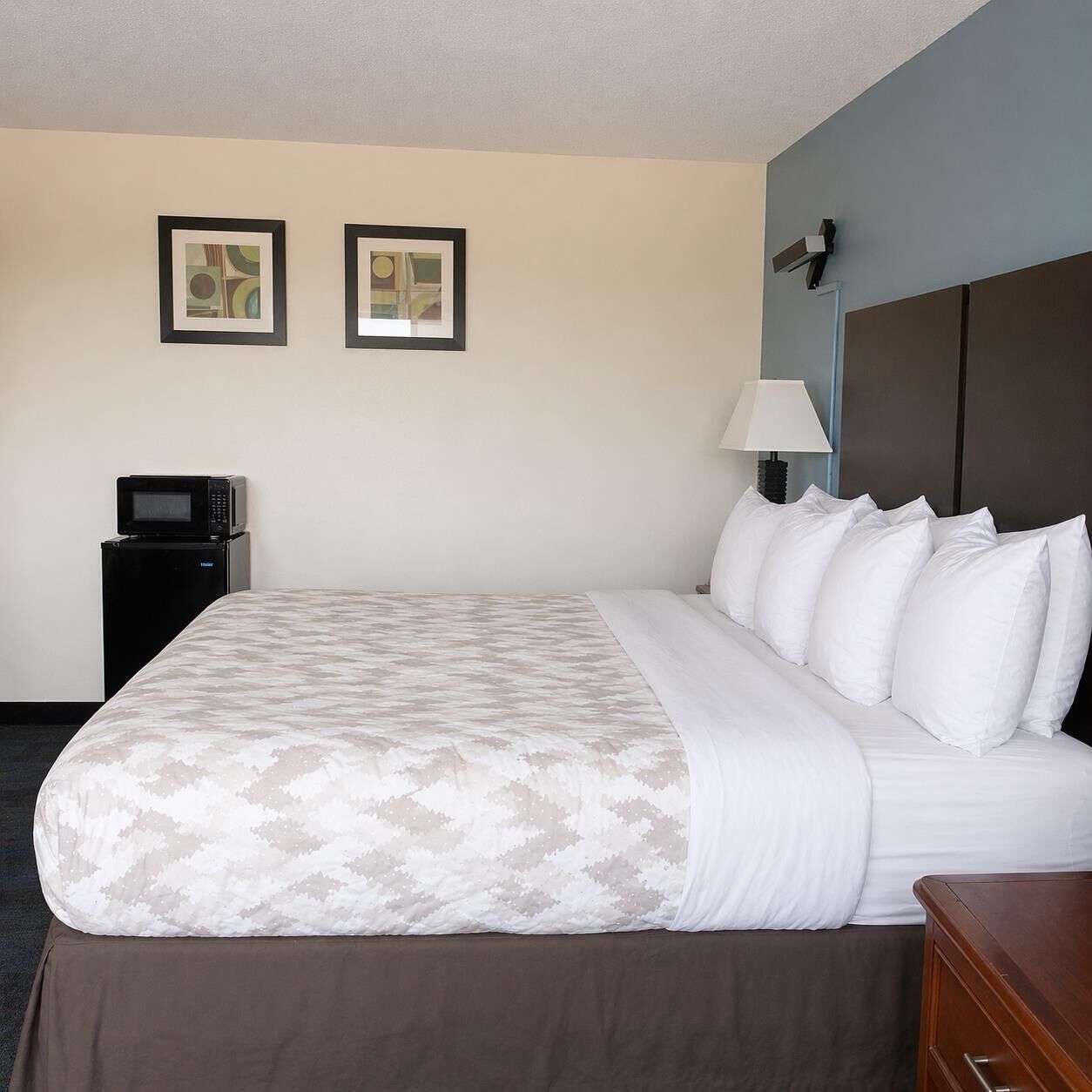 A hotel room with a bed, a bedside lamp, a TV, and two framed pictures on the wall.
