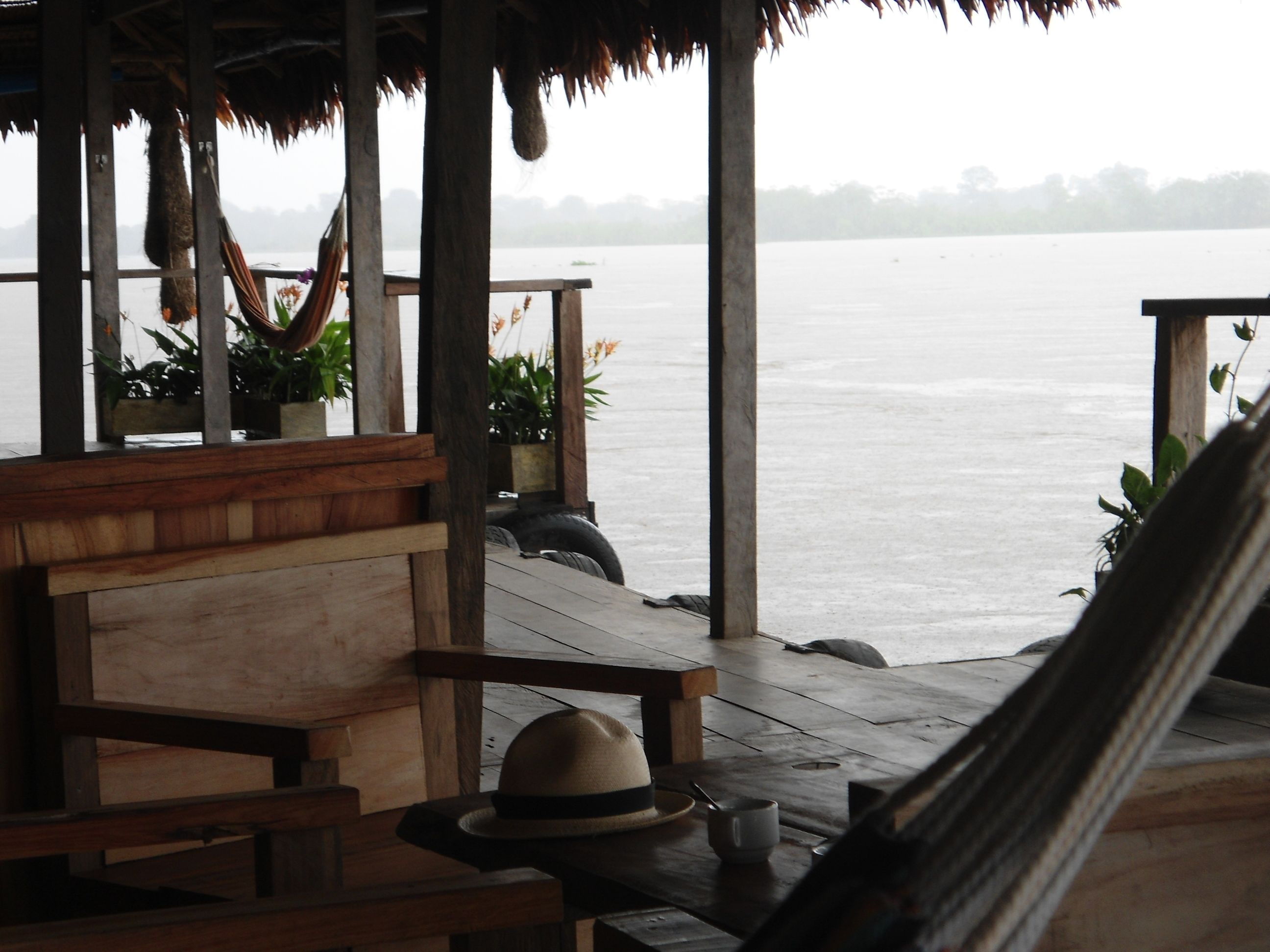 A wooden deck with a hammock, a bench, and a hat on the ground.