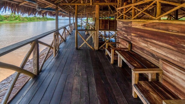 A wooden deck with railings overlooking a river. - Kurupira Cabin Floating (Leticia)