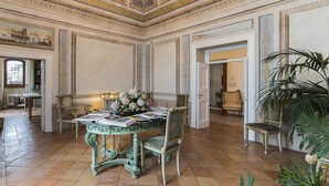 A room with a green ornate table, chairs, and a large plant. - Palazzo Suriano Amalfi Coast (Vietri sul Mare)