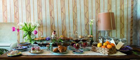 A table set with various pastries, fruits, and a vase of flowers.