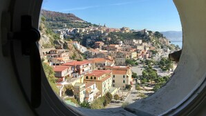 A coastal town viewed through a circular window, featuring a mix of historic and modern buildings, a clear sky, and a hilly backdrop. - Palazzo Suriano Amalfi Coast (Vietri sul Mare)