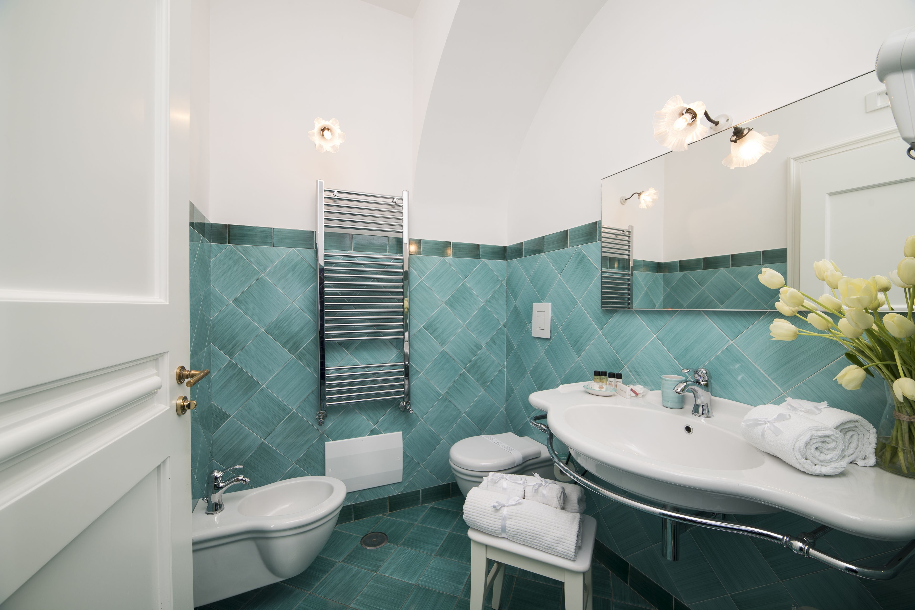 A bathroom with a white sink, a bidet, a toilet, and a towel rack.