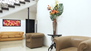 A modern living room with a sofa, armchair, and a decorative vase with flowers. - Hotel Colonial Plaza (Bucaramanga)