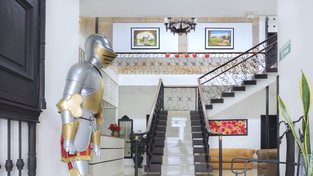 A grand staircase with a chandelier, a large statue, and framed artwork on the walls. - Hotel Colonial Plaza (Bucaramanga)