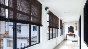 A corridor with large windows, a polished floor, and a wooden console table with a mirror and a small vase. - Hotel Colonial Plaza (Bucaramanga)