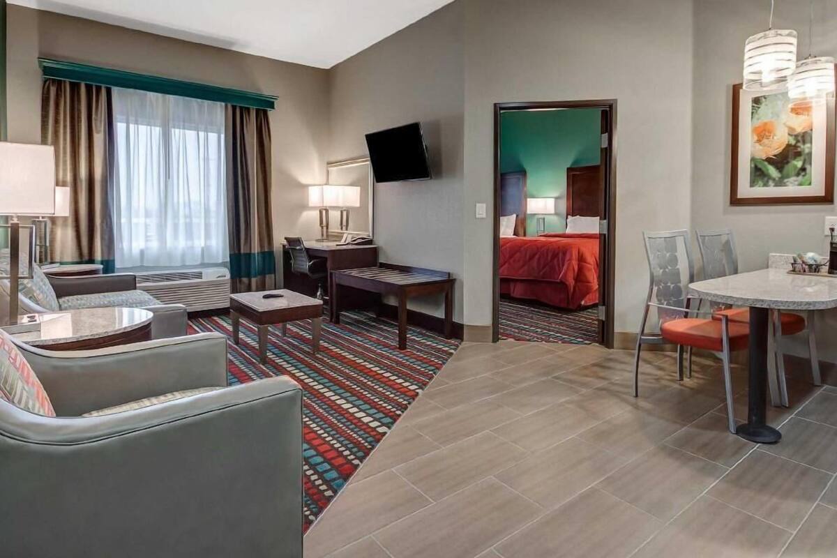 A hotel room with a sofa, a dining table, a TV, and a bed.