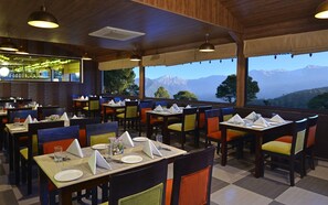 A restaurant with tables set for dining, a bar area, and a view of mountains. - Fortune Park Moksha, Mcleodganj  - Member ITC Hotels' Group (Dharamshala)
