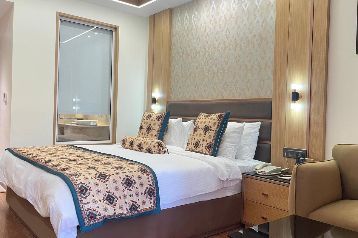 Een hotelkamer met een groot bed, nachtkastjes, een stoel en uitzicht naar buiten.