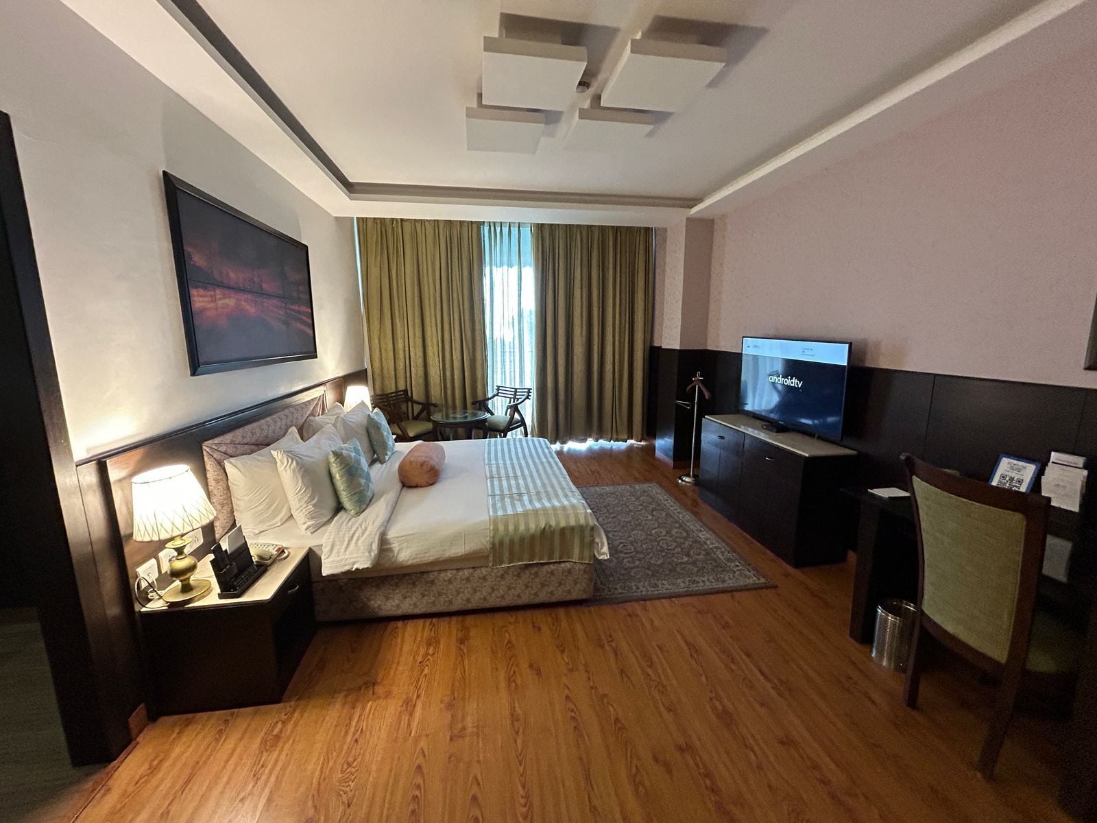 Une chambre d’hôtel avec un lit, un bureau, une télévision et une chaise.