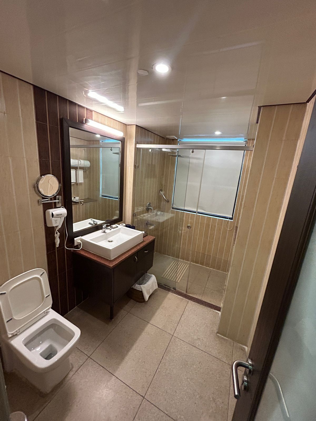 Un baño moderno con inodoro, lavamanos, espejo y ducha.