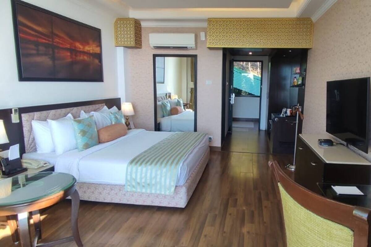 Ein Hotelzimmer mit Bett, Schreibtisch, Fernseher und Spiegel.