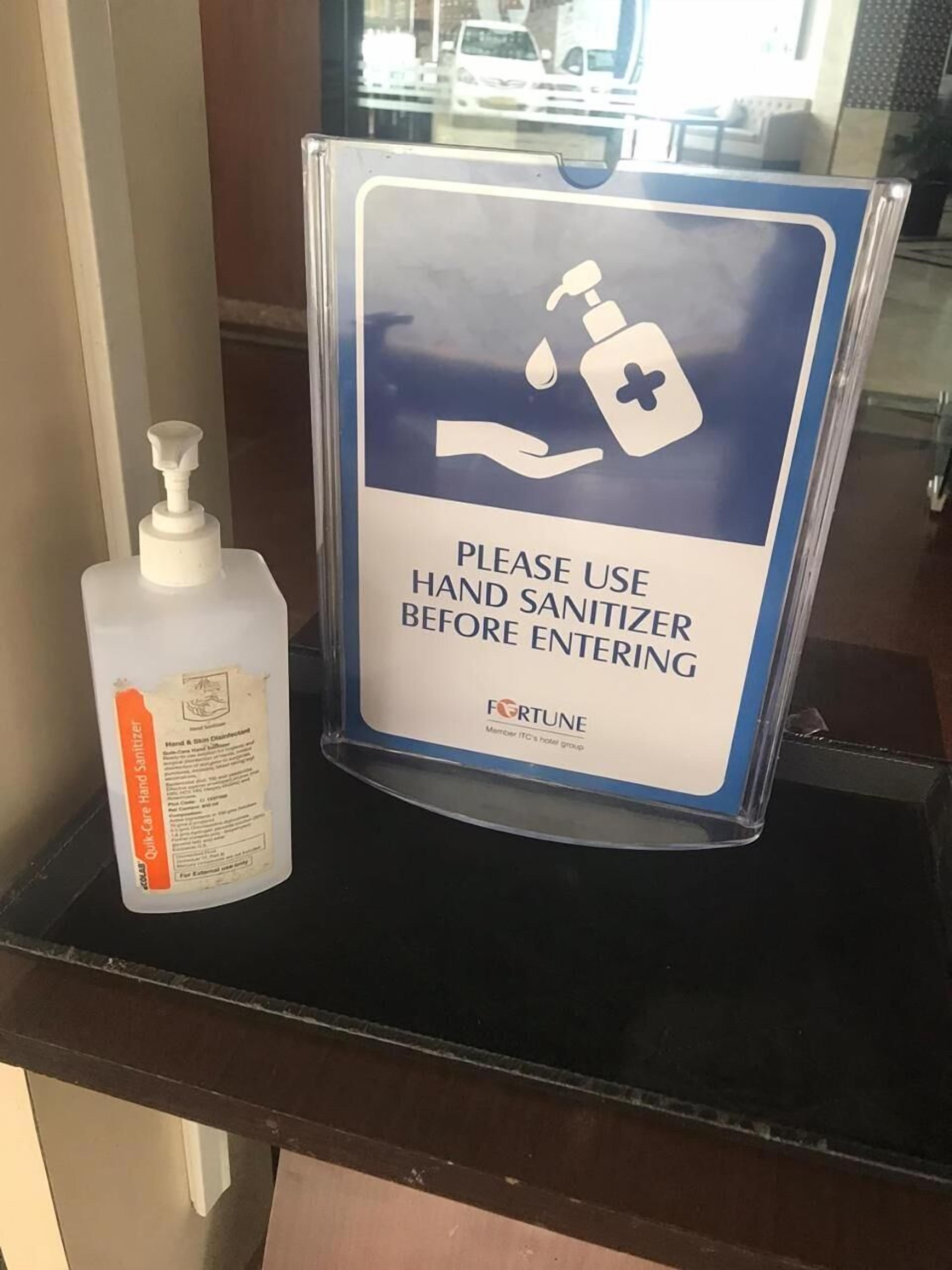 A hand sanitizer dispenser and a sign instructing to use hand sanitizer before entering.