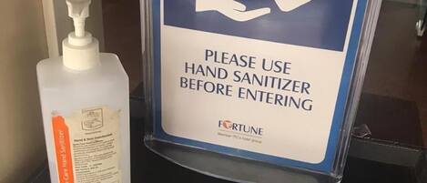 A hand sanitizer dispenser and a sign instructing to use hand sanitizer before entering.