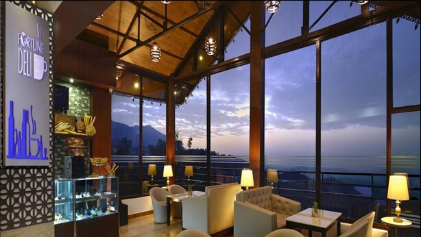 A restaurant with a view of the mountains, large windows, and a bar area. - Fortune Park Moksha, Mcleodganj  - Member ITC Hotels' Group (Dharamshala)