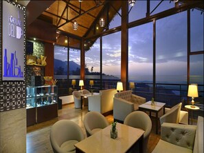 A restaurant with a view of the mountains, large windows, and a bar area. - Fortune Park Moksha, Mcleodganj - Member ITC Hotels' Group (Dharamshala)