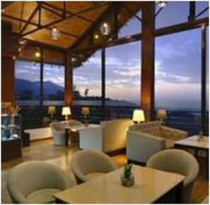 A spacious room with large windows, a high ceiling, and modern furniture. - Fortune Park Moksha, Mcleodganj  - Member ITC Hotels' Group (Dharamshala)