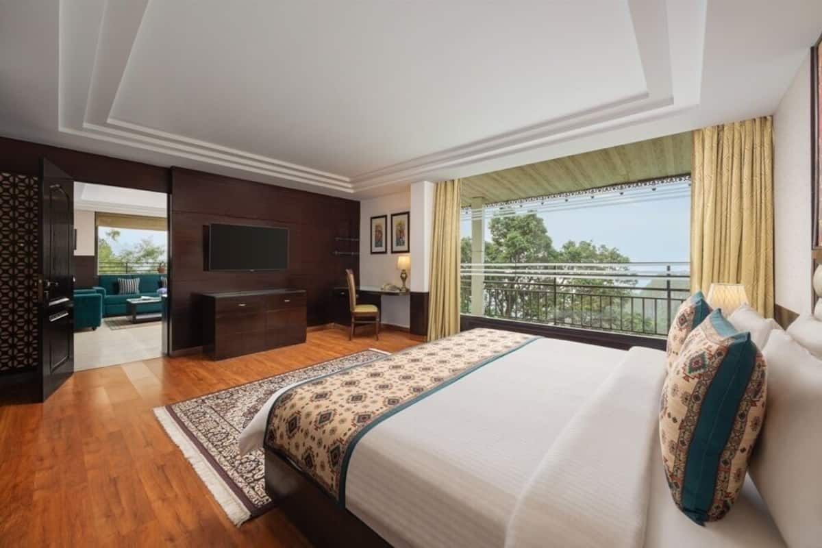 Ein modernes Hotelzimmer mit einem großen Bett, einem Fernseher, einem Balkon mit Aussicht und einer separaten Sitzecke.