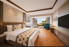 A hotel room with a large bed, a balcony with a view, a TV, and a seating area. - Fortune Park Moksha, Mcleodganj - Member ITC Hotels' Group (Dharamshala)
