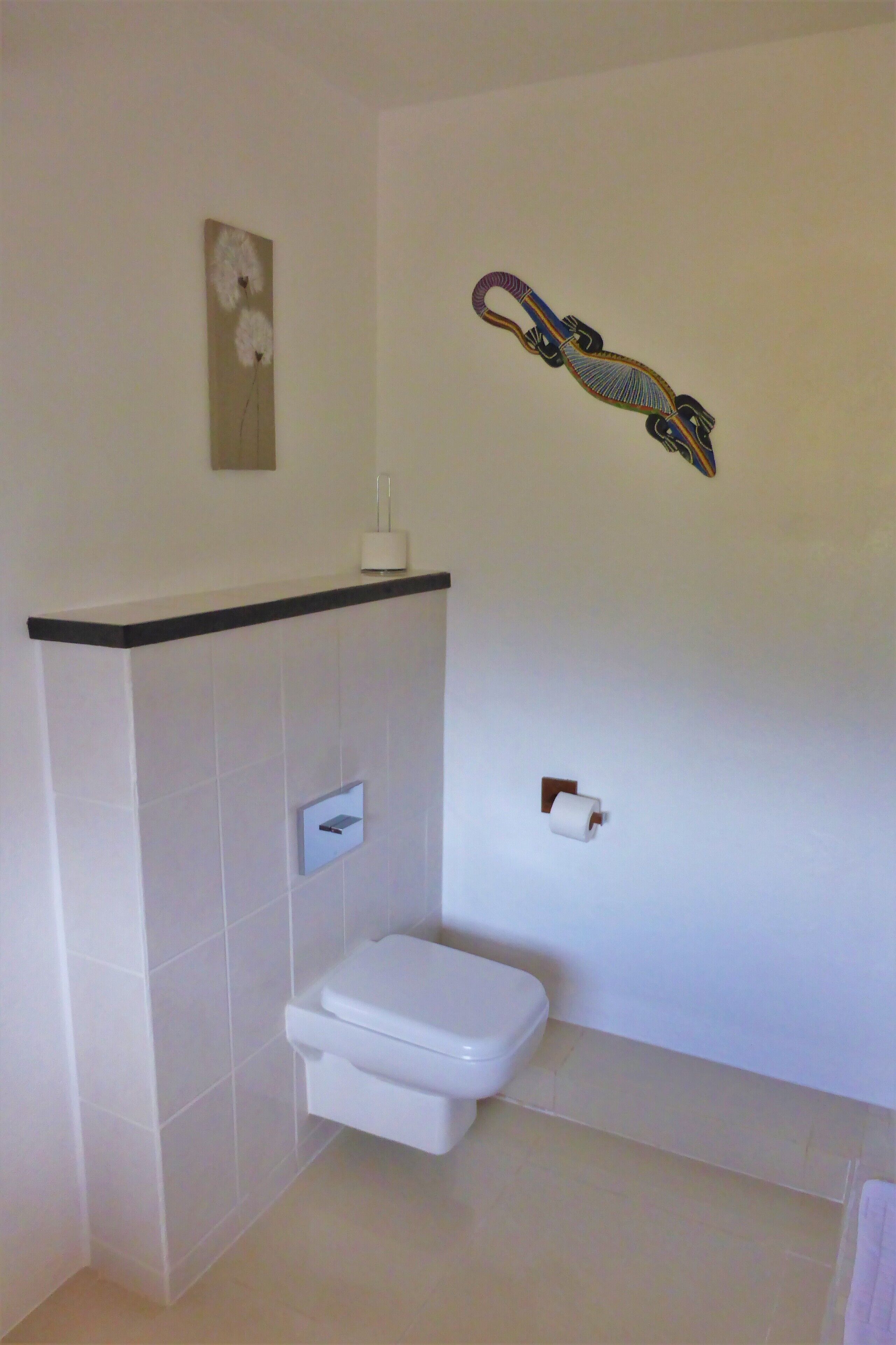 A bathroom with a toilet, a towel rack, and a wall-mounted toilet paper holder.